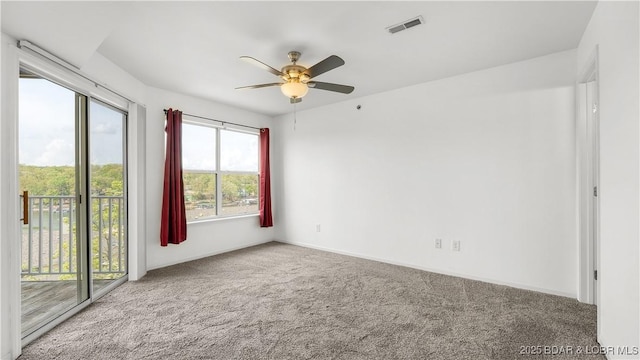 unfurnished room featuring carpet, ceiling fan, visible vents, and baseboards