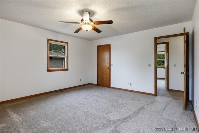empty room with baseboards, a ceiling fan, carpet floors, and a textured ceiling