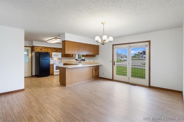 kitchen with brown cabinets, a chandelier, light wood-style flooring, a peninsula, and white appliances