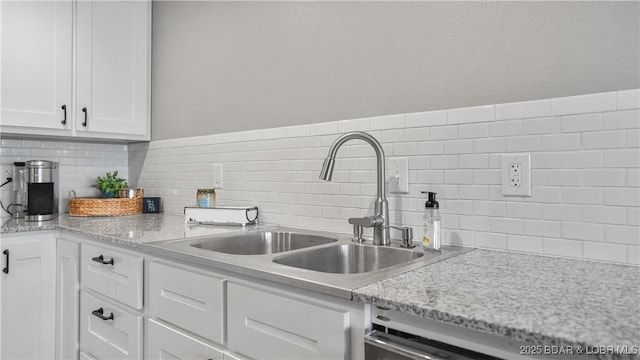 kitchen with a sink, white cabinets, dishwashing machine, and tasteful backsplash