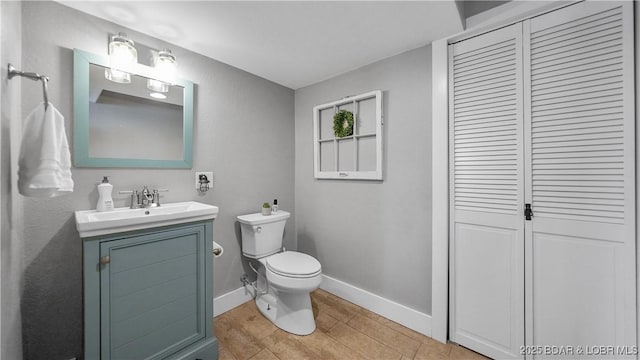 bathroom with baseboards, toilet, a closet, and vanity