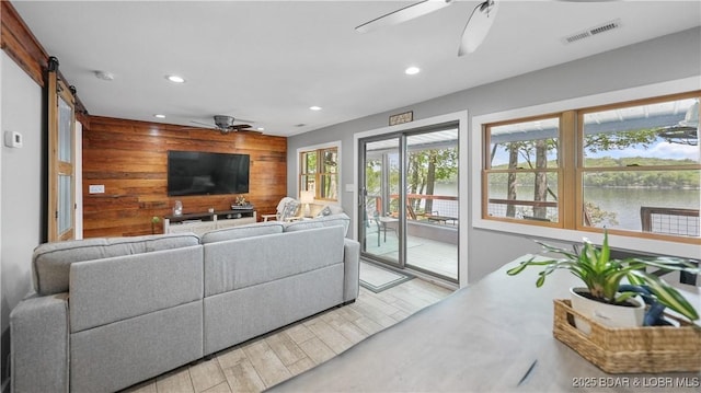 living room featuring recessed lighting, wood finished floors, wood walls, ceiling fan, and visible vents