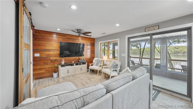 living room featuring wood walls, ceiling fan, light wood-style floors, and recessed lighting