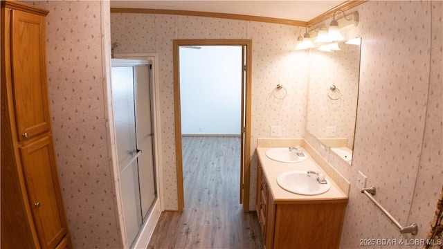 bathroom with crown molding, a sink, wood finished floors, and a shower stall