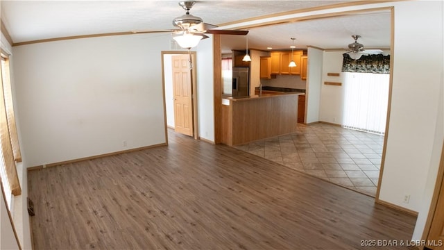 kitchen with stainless steel refrigerator with ice dispenser, ornamental molding, ceiling fan, and dark countertops