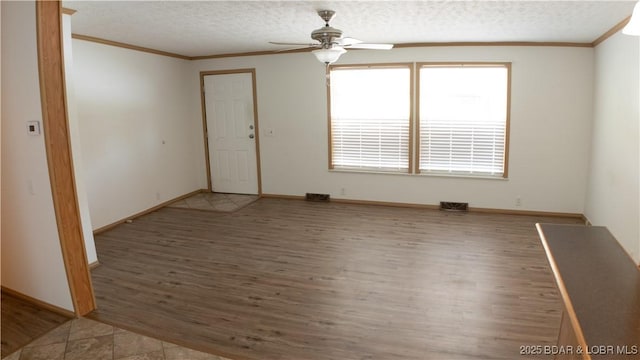 unfurnished room featuring ornamental molding, a ceiling fan, wood finished floors, and visible vents