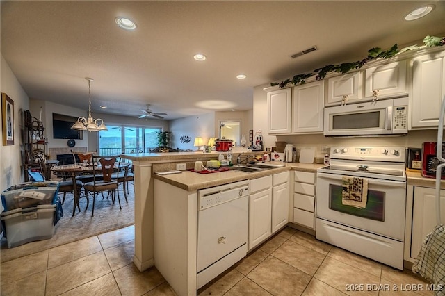 kitchen with a peninsula, white appliances, open floor plan, white cabinets, and a sink