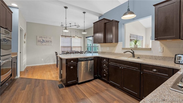 kitchen featuring dark brown cabinetry, tasteful backsplash, stainless steel dishwasher, a sink, and dark wood-style floors