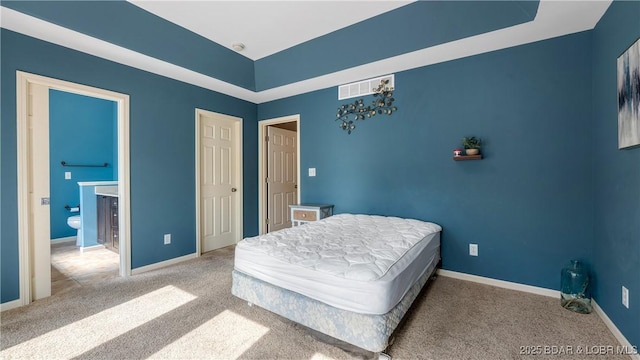 bedroom with baseboards, visible vents, carpet, and ensuite bath