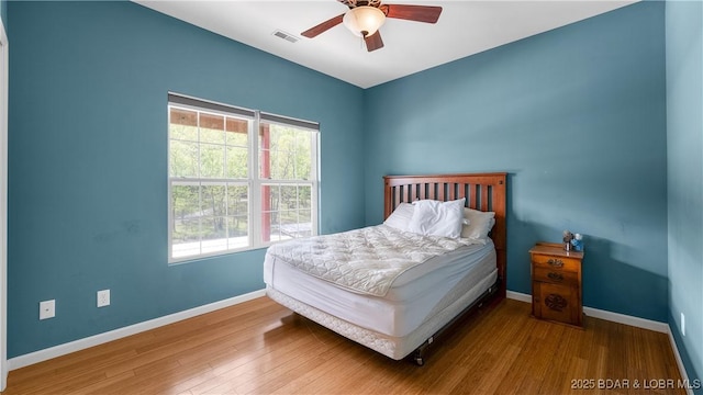bedroom featuring baseboards, a ceiling fan, wood finished floors, and visible vents