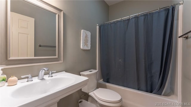 bathroom featuring a sink, shower / bath combo, and toilet