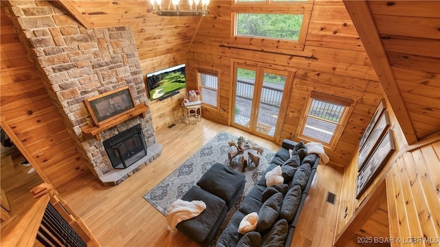 living area with a stone fireplace, wood walls, wood finished floors, and a wealth of natural light
