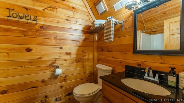 half bath with vanity, wood walls, and toilet
