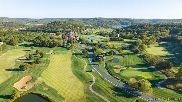 drone / aerial view featuring a water view, view of golf course, and a view of trees