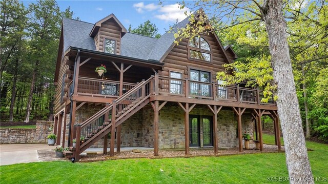rear view of house with a wooden deck, stone siding, stairs, a shingled roof, and a lawn