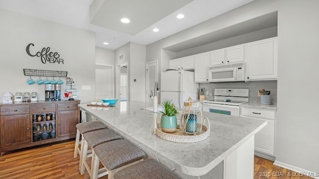 183 Upper Monarch Cove Ct Unit 4E, Lake Ozark, MO 65049 - kitchen with white appliances, a kitchen breakfast bar, white cabinets, and light wood-style floors