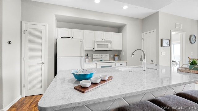 183 Upper Monarch Cove Ct Unit 4E, Lake Ozark, MO 65049 - kitchen with white cabinets, a sink, white appliances, a kitchen breakfast bar, and visible vents