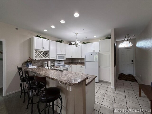 611 Lazy Days Rd Unit R-5, Osage Beach, MO 65065 - kitchen featuring a peninsula, white appliances, a kitchen breakfast bar, white cabinets, and tasteful backsplash