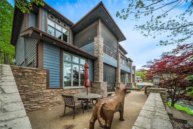 32 Wild Pines Ct, Sunrise Beach, MO 65079 - back of house featuring stone siding, a patio, and outdoor dining area
