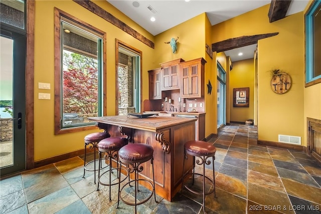 32 Wild Pines Ct, Sunrise Beach, MO 65079 - kitchen featuring stone tile floors, baseboards, wooden counters, and a breakfast bar area