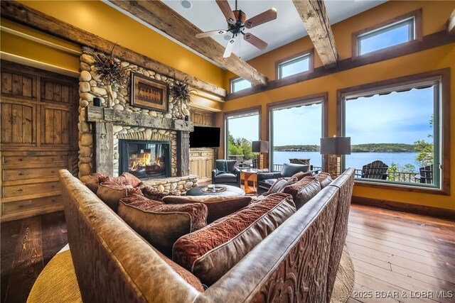 32 Wild Pines Ct, Sunrise Beach, MO 65079 - living room with a stone fireplace, beamed ceiling, wood-type flooring, and ceiling fan