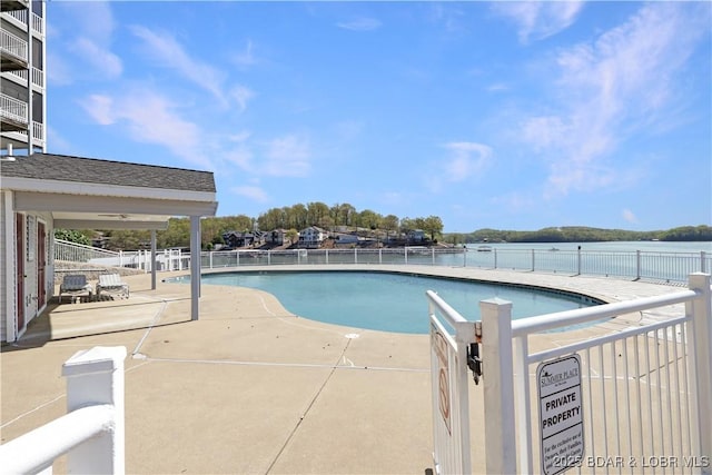 pool featuring a patio, a water view, and fence