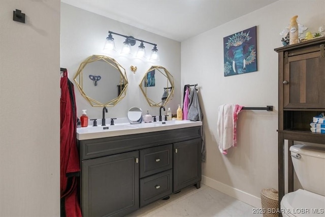 bathroom featuring double vanity, a sink, and toilet