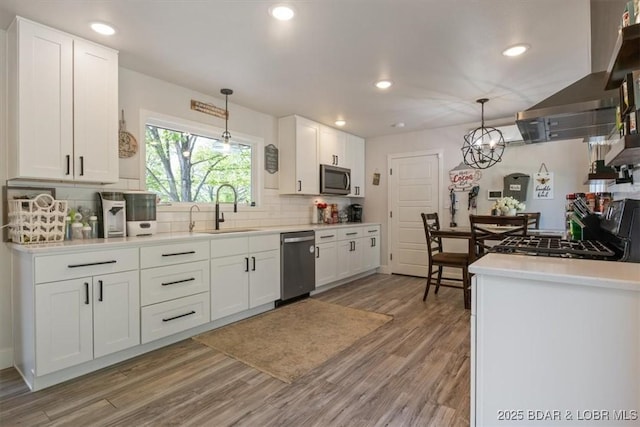 kitchen with light wood-type flooring, white cabinetry, a sink, appliances with stainless steel finishes, and backsplash