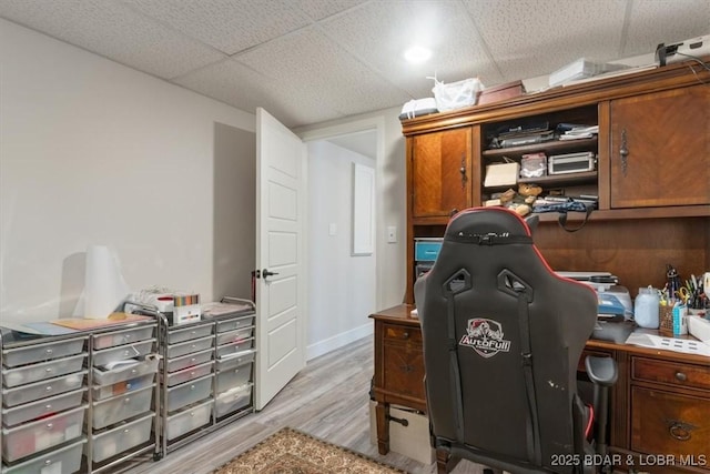 office space with baseboards, a paneled ceiling, and light wood-type flooring