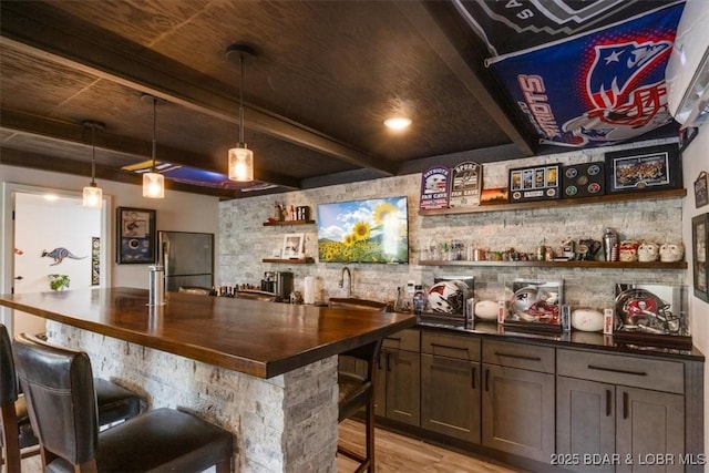 bar featuring freestanding refrigerator, light wood-style flooring, beam ceiling, and decorative light fixtures