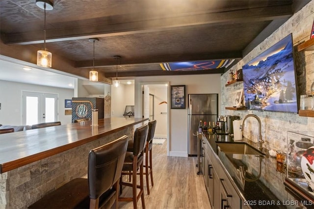 bar featuring bar, beam ceiling, a sink, freestanding refrigerator, and light wood-style flooring