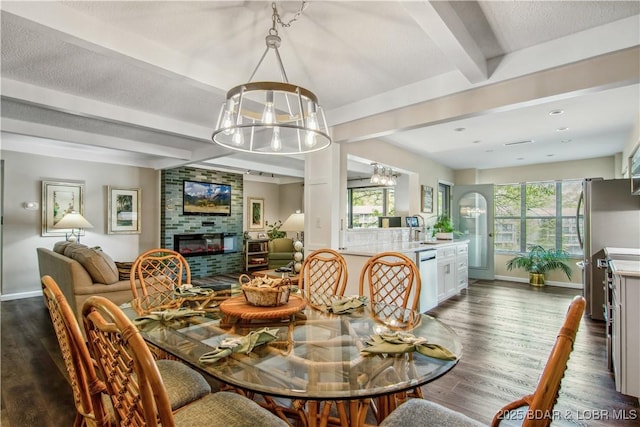 dining area featuring an inviting chandelier, beamed ceiling, baseboards, dark wood-style floors, and a large fireplace