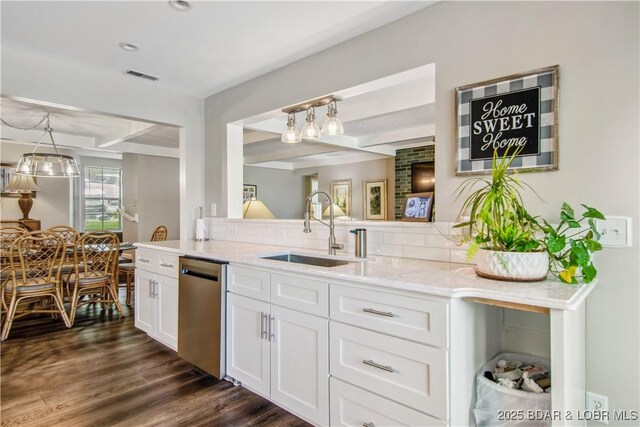 kitchen featuring visible vents, stainless steel dishwasher, white cabinets, a sink, and backsplash