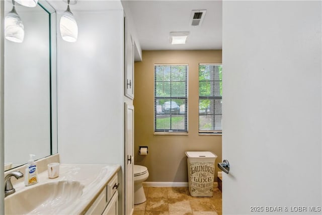 bathroom with baseboards, vanity, toilet, and visible vents