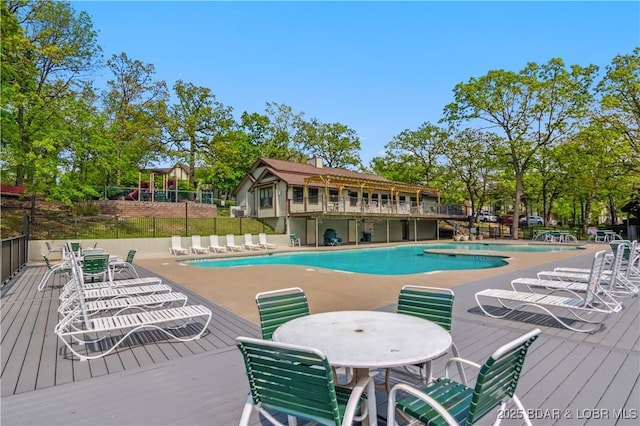 community pool featuring fence, a patio, outdoor dining space, and a deck