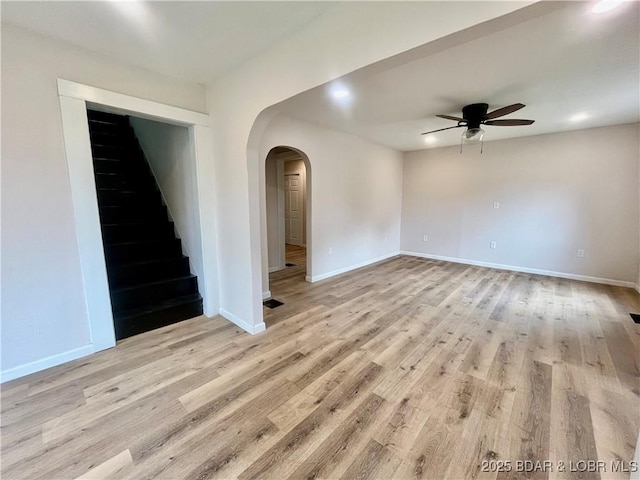 407 Cleveland St, Versailles, MO 65084 - empty room featuring baseboards, light wood-style floors, ceiling fan, stairway, and arched walkways
