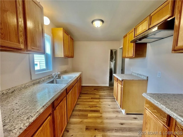 407 Cleveland St, Versailles, MO 65084 - kitchen with brown cabinetry, light wood-type flooring, a sink, baseboards, and under cabinet range hood