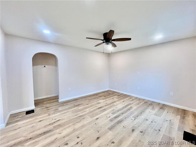 407 Cleveland St, Versailles, MO 65084 - empty room featuring baseboards, a ceiling fan, arched walkways, and wood finished floors