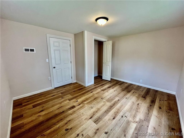 407 Cleveland St, Versailles, MO 65084 - unfurnished bedroom featuring baseboards, visible vents, wood finished floors, and a closet