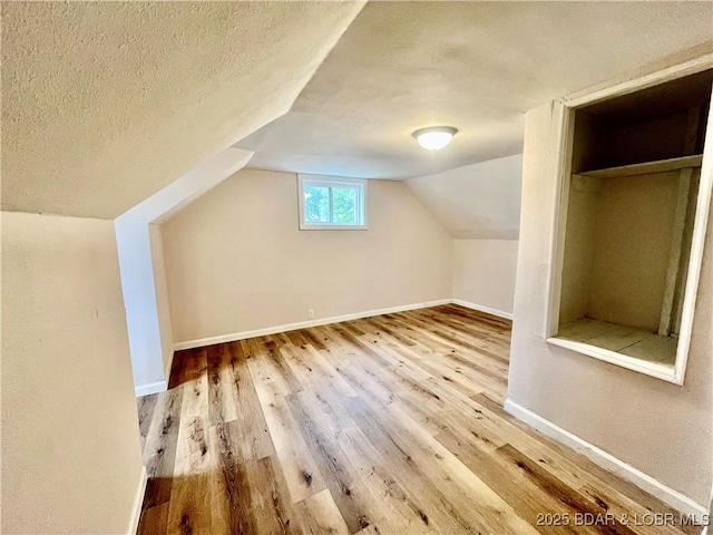 407 Cleveland St, Versailles, MO 65084 - bonus room with a textured ceiling, baseboards, vaulted ceiling, and wood finished floors
