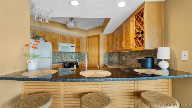32 Cedar Ct Unit 3A, Lake Ozark, MO 65049 - kitchen featuring white appliances, a peninsula, a textured ceiling, and decorative backsplash