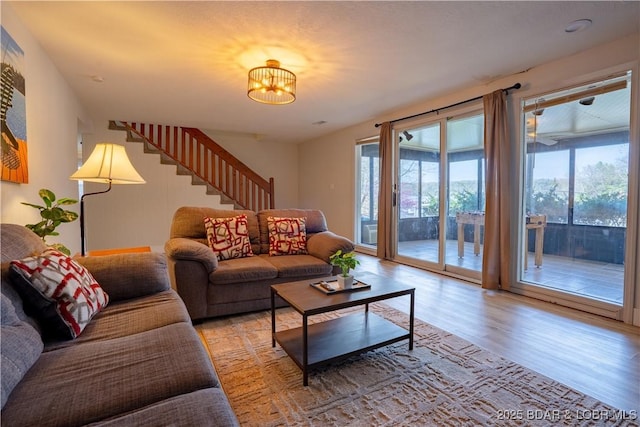 living room featuring light wood-style floors, an inviting chandelier, and stairs