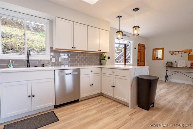 kitchen with a sink, light wood-style floors, light countertops, a peninsula, and stainless steel dishwasher