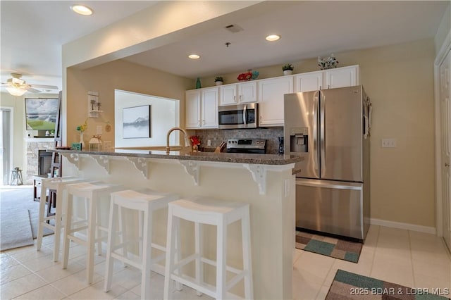 kitchen featuring appliances with stainless steel finishes, white cabinets, backsplash, and dark stone countertops