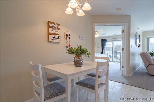 dining room featuring light colored carpet, baseboards, ceiling fan with notable chandelier, and light tile patterned floors
