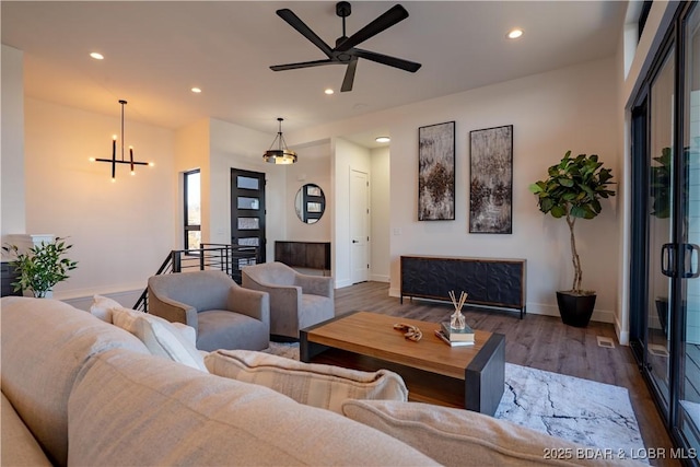 living area featuring recessed lighting, baseboards, wood finished floors, and ceiling fan with notable chandelier