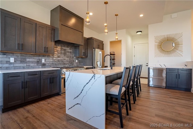 kitchen featuring a sink, premium range hood, high quality appliances, and wood finished floors