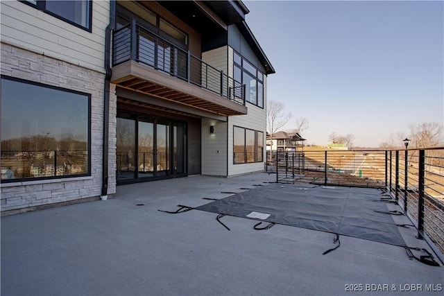 view of patio / terrace featuring fence and a balcony