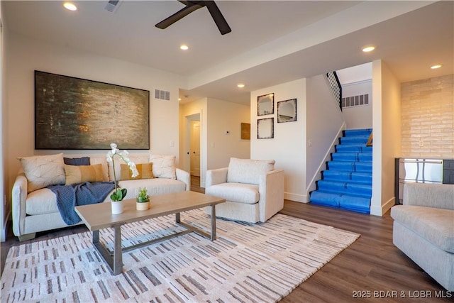 living area with visible vents, a ceiling fan, wood finished floors, and stairway