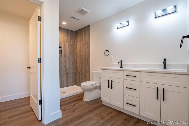full bathroom featuring visible vents, a sink, a tile shower, and toilet